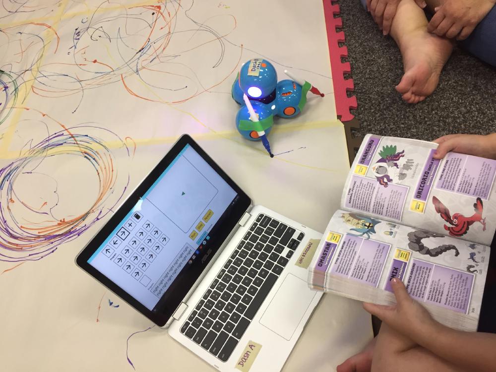Accessible coding Young learner holding a book and working with a coding environment on their laptop